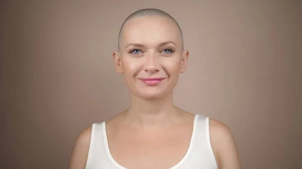 Beautiful bald woman looking at the camera and smiling. copy space, beige background — Stock Photo, Image