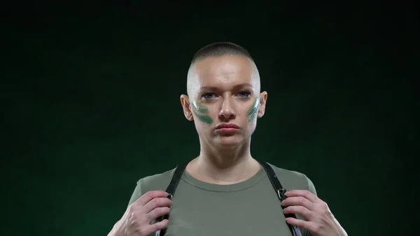 Portrait of a bald woman in military camouflage makeup and harness looking at the camera and posing. copy space — Stock Photo, Image