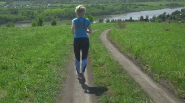 Tepedeki tarlada koşan ince bir kadın, dikiz manzaralı.