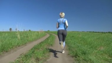 Tepedeki tarlada koşan ince bir kadın, dikiz manzaralı.