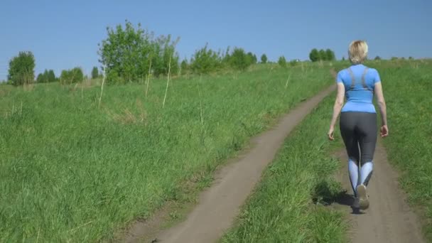 Vacker smal kvinna idrottsman är på planen efter en körning. Bakifrån — Stockvideo