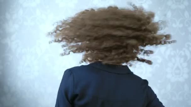 Жінка в окулярах з кучерявим волоссям крутить голову, вітер у волоссі — стокове відео
