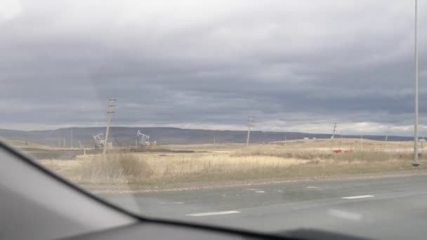 Derricks de petróleo a lo largo de la carretera. vista desde la ventana del coche — Vídeo de stock