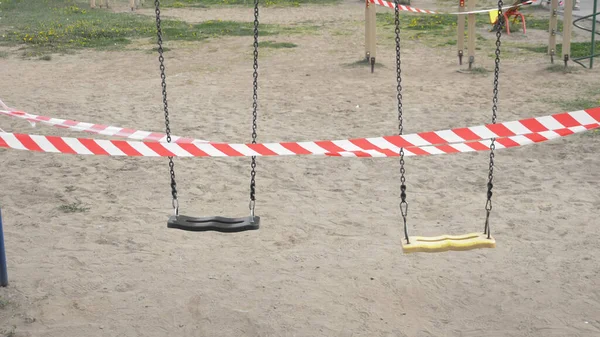 Empty playground during the coronavirus pandemic. warning tapes on the rides — Stock Photo, Image