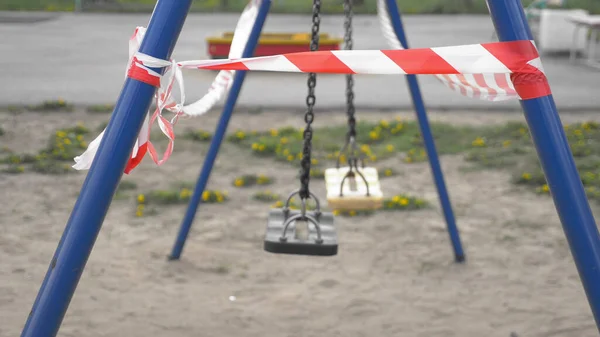 Empty playground during the coronavirus pandemic. warning tapes on the rides — Stock Photo, Image