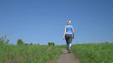 Tepedeki tarlada koşan ince bir kadın, dikiz manzaralı.