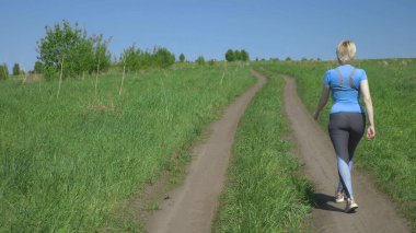 Tepedeki tarlada koşan ince bir kadın, dikiz manzaralı.
