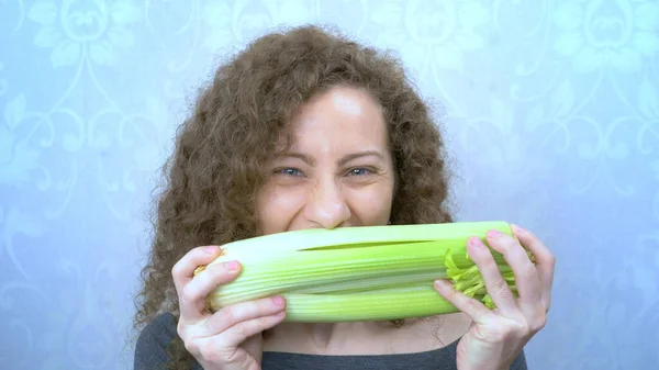 Retrato de una hermosa chica comiendo felizmente tallos de apio — Foto de Stock