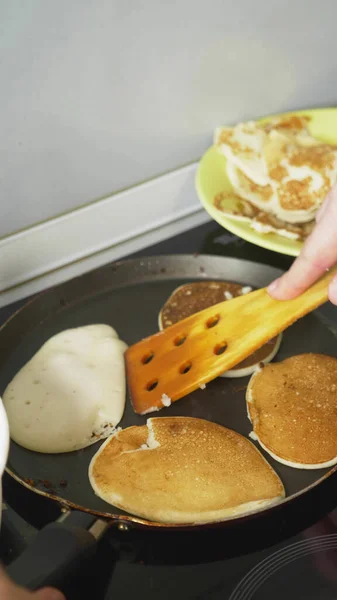 vertically. close up, someone is cooking pancakes in a pan on a stove touch