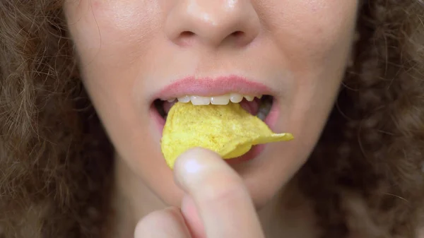 Κλείσε τα χείλη σου. όμορφη σγουρή κοπέλα με ευχαρίστηση τρώει πατατάκια — Φωτογραφία Αρχείου