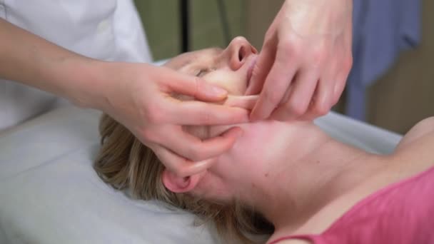 Masażysta daje kobiecie anti-aging masaż twarzy w spa — Wideo stockowe