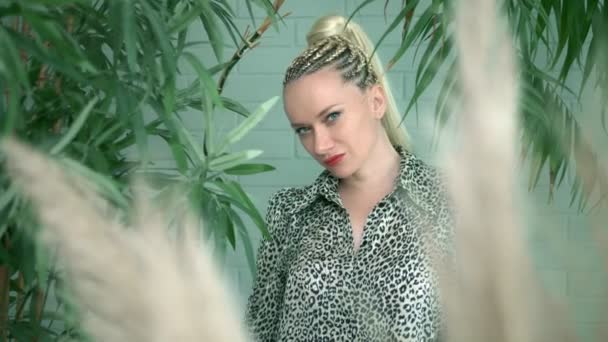 Hermosa mujer con trenzas afro posando entre plantas tropicales verdes — Vídeos de Stock