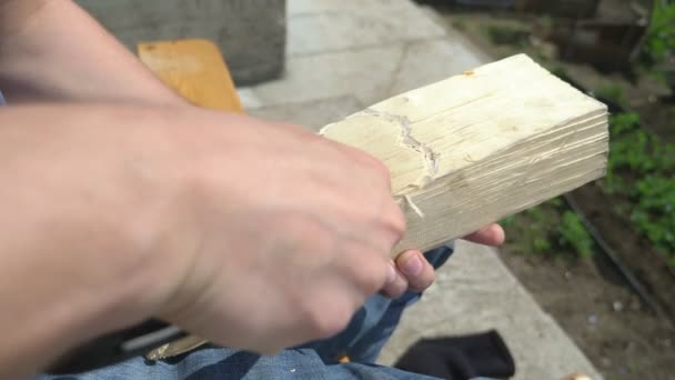 Doe dicht. man snijdt een hart teken met een mes op een houten plank, buiten — Stockvideo