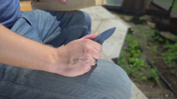 Gros plan. homme découpe des motifs avec un couteau sur une planche de bois, à l'extérieur — Video