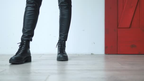 Gros plan. jambes féminines en cuir noir skinny et bottes sur fond blanc rouge — Video