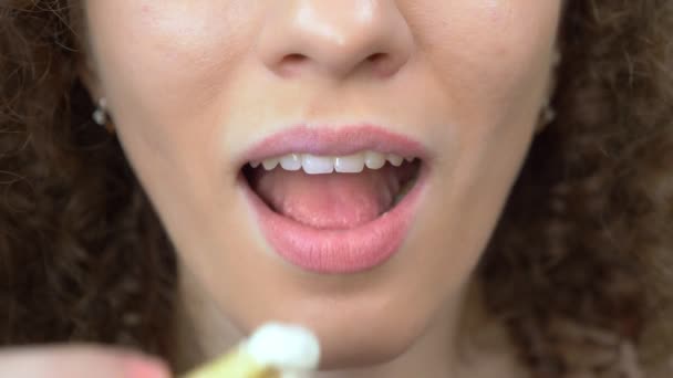 Gros plan de la bouche. belle fille aux cheveux bouclés mange des frites — Video