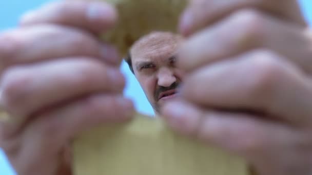 Hombre calvo bigotudo hace un agujero en una tabla de madera con un cuchillo al aire libre — Vídeos de Stock