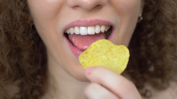 Närbild av läpparna. vacker lockig flicka med glädje äter potatis chips — Stockvideo