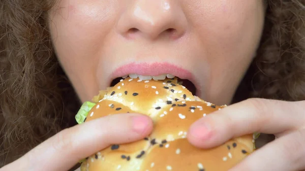巻き毛のきれいな女がジューシーなハンバーガーを食べる。閉鎖だ — ストック写真