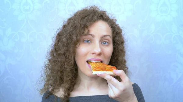 Retrato. mulher morde um pedaço de pizza com um sorriso — Fotografia de Stock