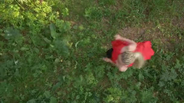 Vue d'en haut. femme en cape rouge court à travers la forêt. vent fort souffle — Video