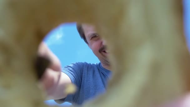 Kale man met snor snijdt een gat in een houten plank met een mes buiten — Stockvideo