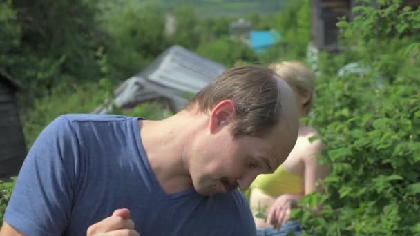 Auf dem Land läuft eine Nachbarin im Badeanzug an einem Mann im Garten vorbei — Stockvideo