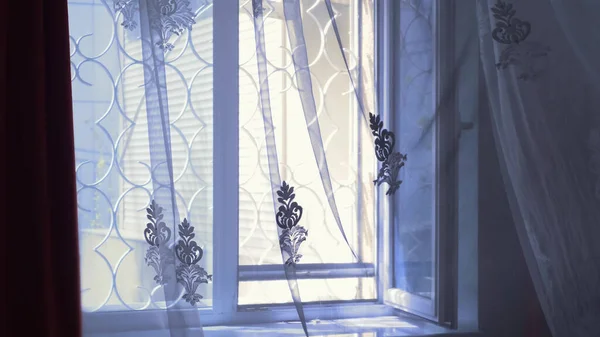 Průhledné okenní rolety s tepanými železnými mřížemi jemně pohnutými větrem — Stock fotografie