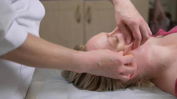 Masajista da mujer anti-envejecimiento masaje facial en el spa — Foto de Stock