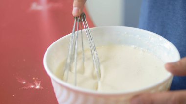 Yakın plan. Bir adam un ile yumurta çırpar. Ev mutfağında tatlı yap.