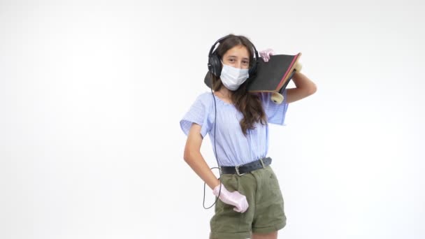 Geïsoleerde witte achtergrond. meisje in handschoenen en een medisch masker met een skateboard — Stockvideo