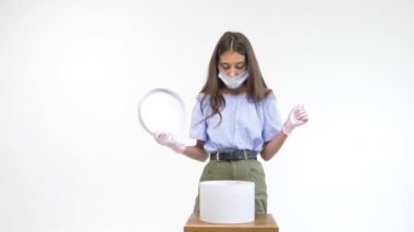 Eldiven giymiş güzel bir kız ve tıbbi bir maske hediye kutusunu açıyor.