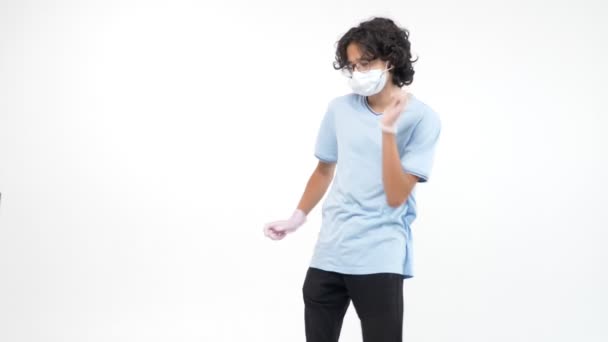 Isolerad vit bakgrund. tonårspojken i en medicinsk mask och handskar dansar — Stockvideo