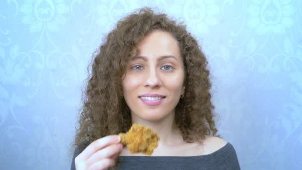 Portret. krullend harig meisje eten gebakken kip drumstick — Stockvideo