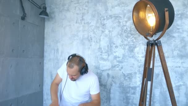 En man i hörlurar skriver elektronisk musik med ett midi-tangentbord och bärbar dator — Stockvideo