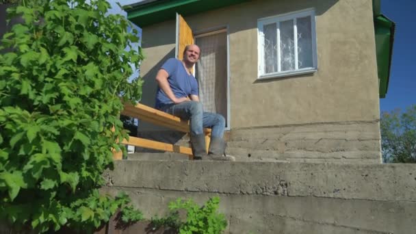 Glatzköpfiger Mann draußen vor blauem Himmel und Dorfhaus — Stockvideo