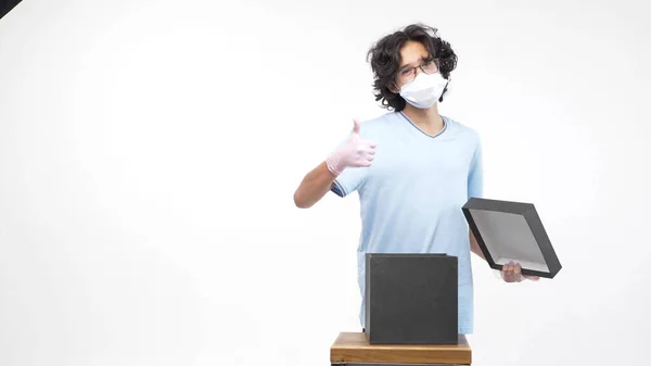 Isolated white background. boy in gloves and a medical mask opens a gift box — Stock Photo, Image