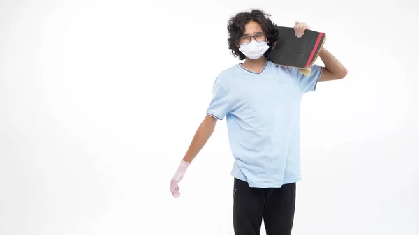 Isolerad vit bakgrund. pojke i handskar och en medicinsk mask med en skateboard — Stockfoto