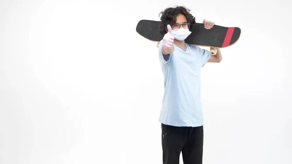 Fundo branco isolado. menino de luvas e uma máscara médica com um skate — Fotografia de Stock