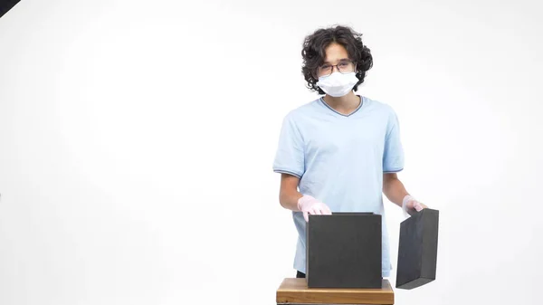 Isolated white background. boy in gloves and a medical mask opens a gift box — Stock Photo, Image