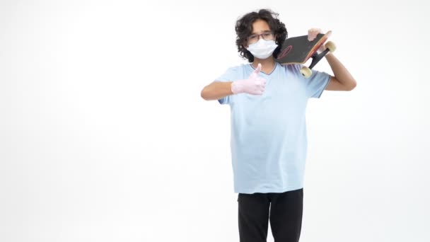 Izolované bílé pozadí. chlapec v rukavicích a lékařská maska s skateboardem — Stock video