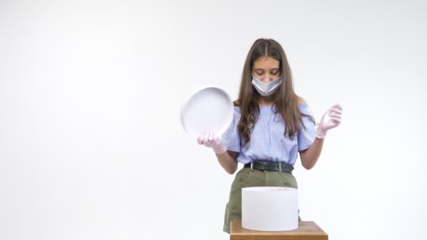 Όμορφο κορίτσι με γάντια και μια ιατρική μάσκα ανοίγει ένα κουτί δώρου — Αρχείο Βίντεο