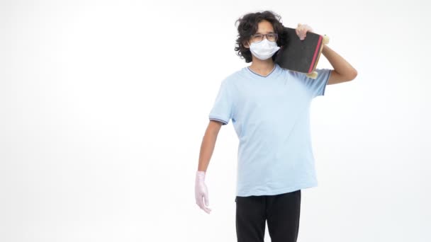 Odizolowane białe tło. chłopiec w rękawiczkach i maska medyczna z deskorolką — Wideo stockowe