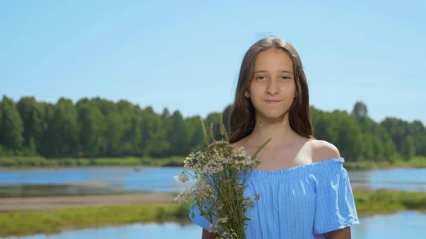 Chica con el pelo largo mira a la cámara en el fondo del río —  Fotos de Stock