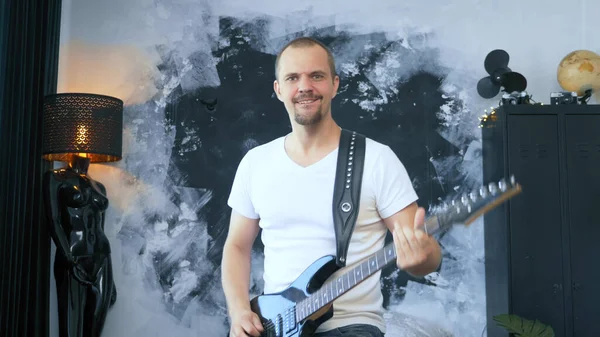 Красивый мужчина рок-музыкант играет на электрогитаре в стилизованной студии — стоковое фото