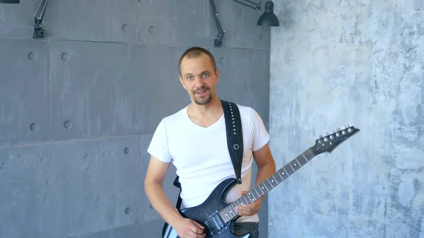 Handsome man rock musician plays an electric guitar in a stylized studio — Stock Photo, Image