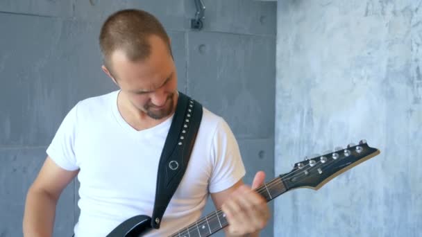 Homem bonito músico de rock toca uma guitarra elétrica em um estúdio estilizado — Vídeo de Stock