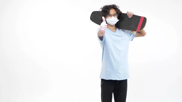 Geïsoleerde witte achtergrond. jongen in handschoenen en een medisch masker met een skateboard — Stockfoto