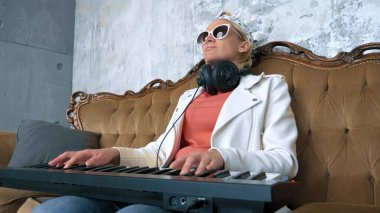 Garip insanlar. Komik kadın DJ dizüstü bilgisayarlı ve Midi klavyeli müzik yazıyor.