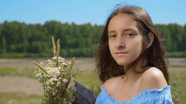 Mädchen mit langen Haaren auf einem Feld, das in die Kamera blickt — Stockfoto